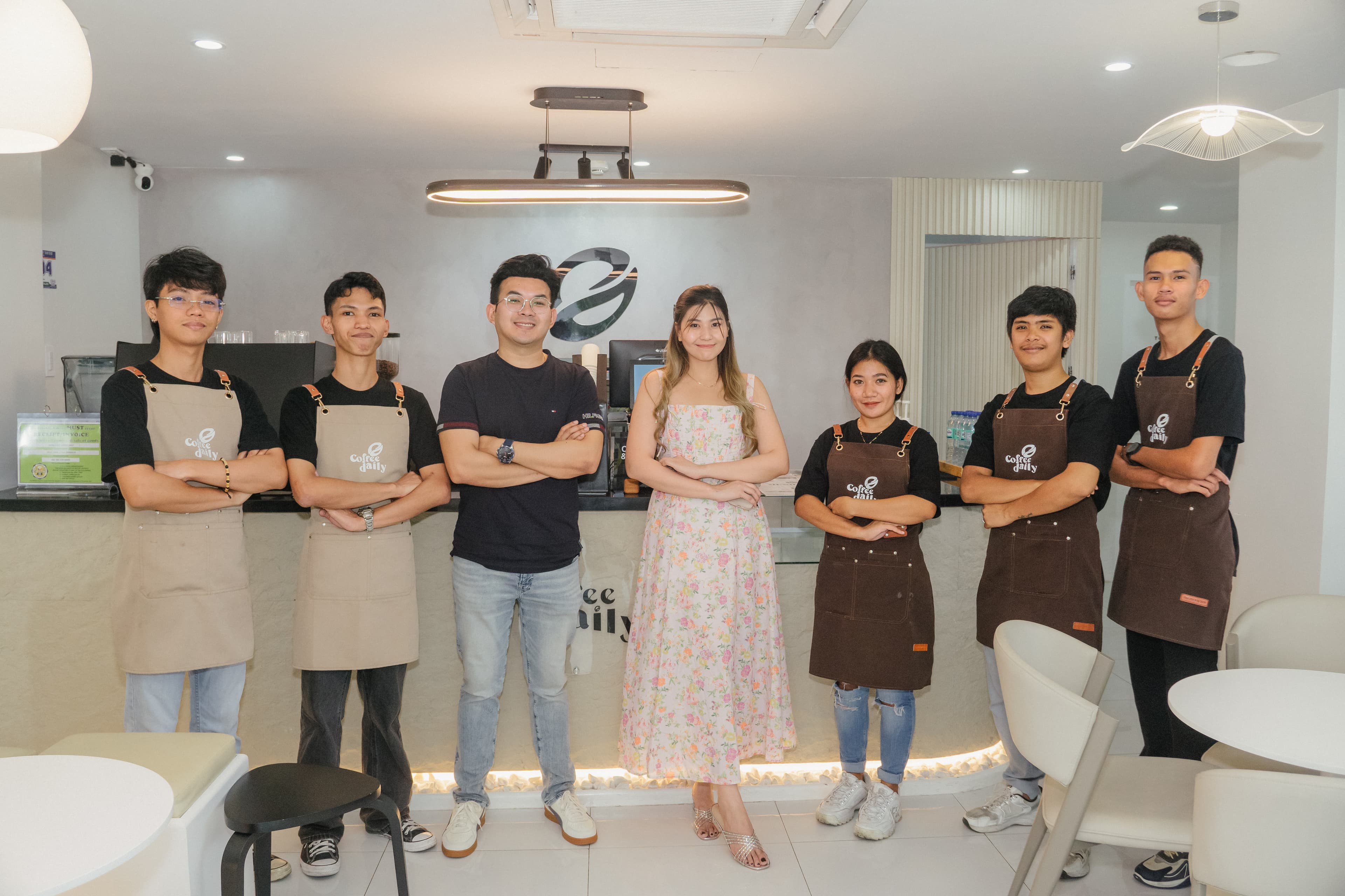 Seven smiling staff and owners pose together inside a modern, brightly lit coffee shop.